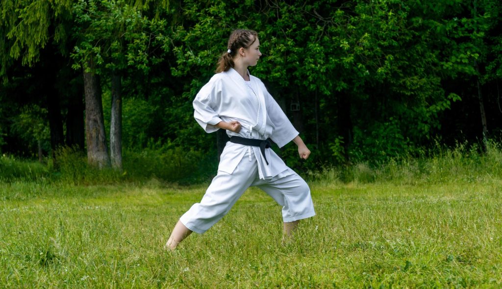 Kata practice in a karate gi - The Karate Shop Karate student performing gedan barai, a downward block, in a white karate gi.