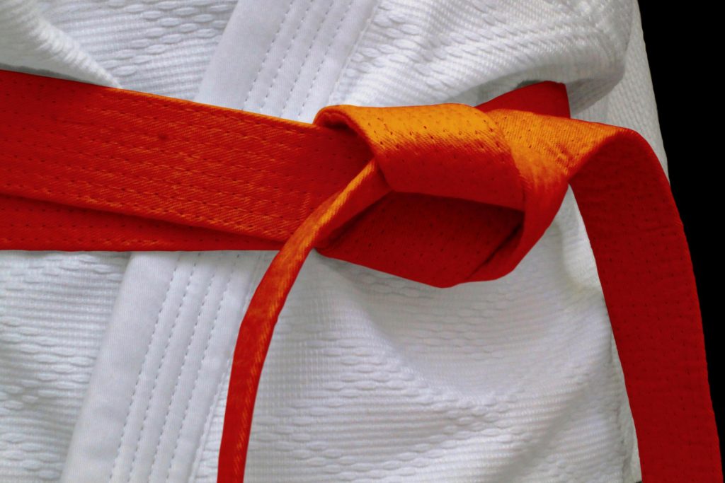 Orange karate belt tied around a gi - The Karate Shop Orange karate belt knotted around a white gi, showing how the belt wraps and ties.